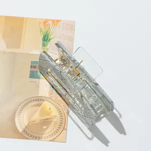 Detail view of a quilted gray-blue hair claw clip with a golden metal spring on a magazine