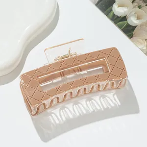 Detail of a beige rectangular hair claw clip with a classic quilted lattice pattern