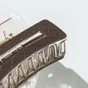 Detailed macro view of checkered pattern and golden spring on resin hair claw clip