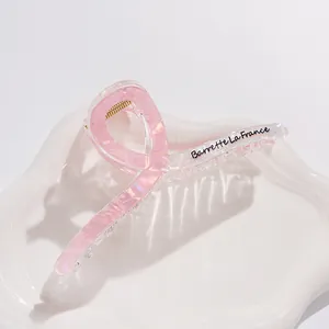 Dettaglio macro della pinza per capelli rosa perlato da 13cm con molla dorata