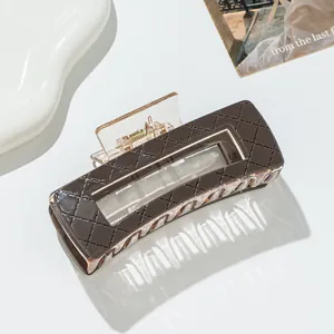 Close-up of a dark brown checkered claw clip with a hollow rectangular design and gold spring