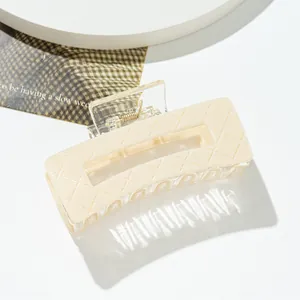 Macro detail of a cream rectangular hair claw clip featuring an embossed quilted pattern