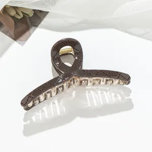 Détail d'une grande pince à cheveux marron foncé à motif de losanges et ressort doré