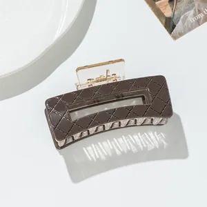 Detail view of brown rectangle hair claw with lattice pattern and strong gold metal spring