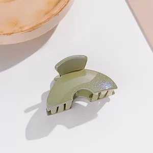 Gros plan d'une petite pince à cheveux verte scintillante avec finition brillante et forme d'éventail