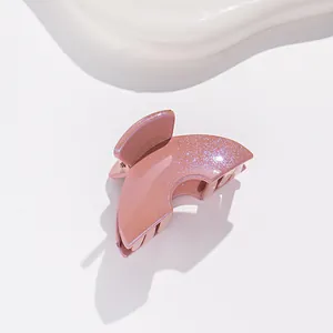 Détail d'une pince à cheveux rose pailletée avec finition en résine et design festonné