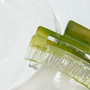 Square acrylic hair claw clip with green gradient and translucent finish on ceramic surface