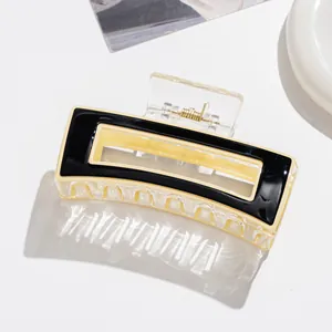Détail de la pince à cheveux carrée en acétate avec bord noir et intérieur jaune crème