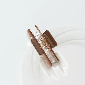 Detail of square brown gradient acrylic hair claw clip with golden metal spring on white plate