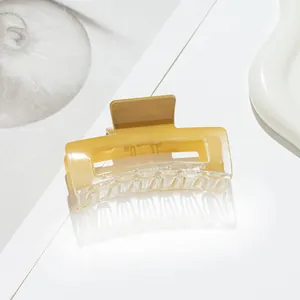 Macro detail of amber acrylic square hair claw clip with transparent glossy finish