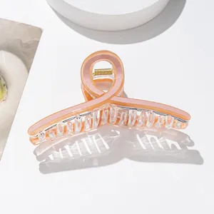 Close-up of translucent peach acetate hair claw clip with elegant twisted ring design