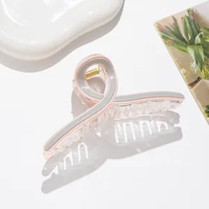 Macro detail of large acetate hair claw clip showing gold spring and pink striped texture