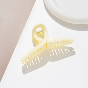 Détail macro d'une grande pince à cheveux mate crème avec ressort en métal et design croisé