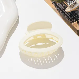 Macro view of matte cream oval hair claw clip with smooth texture and sturdy teeth