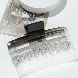 Macro shot of large gradient hair claw clip with rectangular hollow design on art magazine