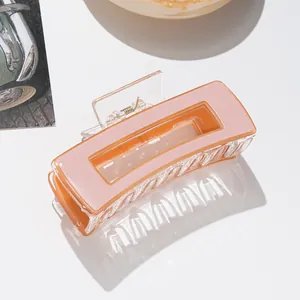 Detail einer pink-orangen rechteckigen Haarklammer mit goldener Metallfeder