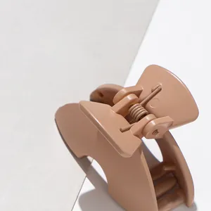 Macro detail of matte resin hair claw in nude beige with durable metal spring mechanism