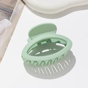 Detail of matte mint green oval hair claw clip on a stylish ceramic tray background