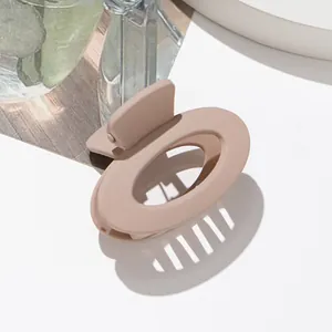 Dettaglio della pinza per capelli ovale opaca beige con eleganti giochi d'ombra