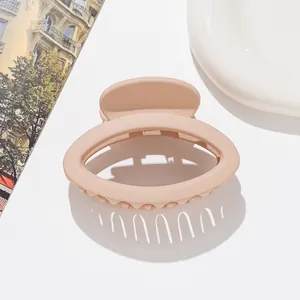 Close-up of small matte oval hair claw clip in apricot finish with round plastic teeth