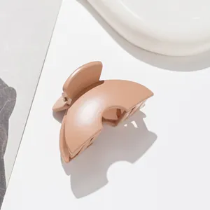 Close-up of matte beige hair claw clip with metal spring on a clean white surface
