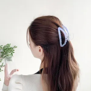 Blue translucent hair claw clip with black calligraphy design on a half-up hairstyle
