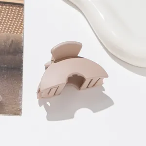 Macro view of matte beige hair claw clip with elegant arched design on a ceramic tray