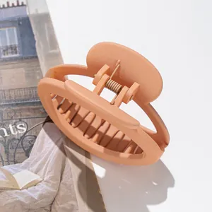 Detail of a matte apricot oval hair claw clip with a strong metal spring and bite-teeth