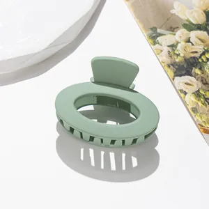 Dettaglio macro di un fermaglio per capelli ovale verde salvia opaco con denti