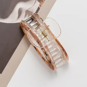 Detailed close-up of an amber resin hair claw with black calligraphy and gold spring