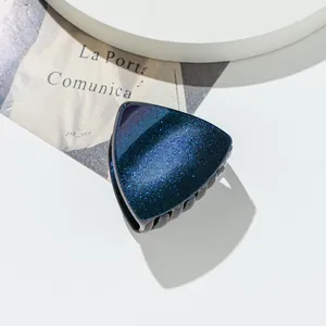 Detailed view of a dark blue glitter cat ear hair claw clip with black shark teeth grip