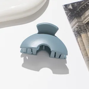 Detailed view of a matte grey-blue half-round hair claw clip on a clean white background