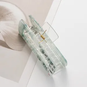 Detailed macro view of mint marble acrylic hair claw with elegant black calligraphy