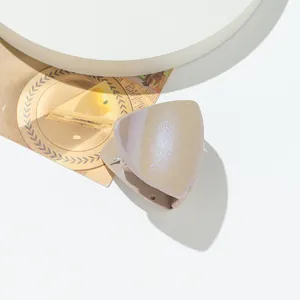 Macro shot of glittery triangular claw clip on a minimalist display stand