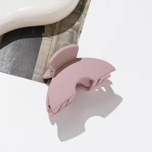 Macro detail of a dusty pink matte claw clip with a minimalist hollow design and metal spring
