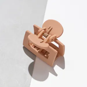 Détail d'une pince à cheveux carrée mate beige avec centre évidé et ressort en métal