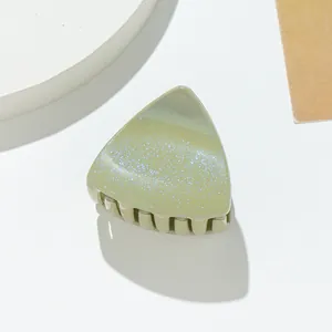 Macro shot of a light green glitter cat ear hair claw clip with a glossy sequin texture
