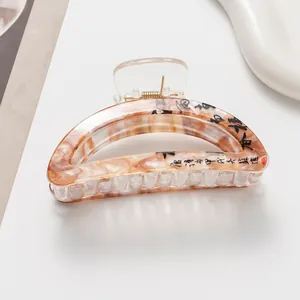 Detail of large brown marble hair claw clip with elegant black Chinese calligraphy