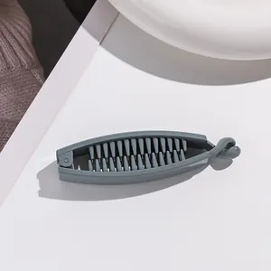 Détail de la pince banane mate grise avec dents denses et fermeture à crochet
