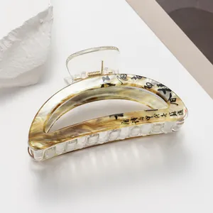 Macro detail of marble pattern hair claw clip with black artistic calligraphy decoration