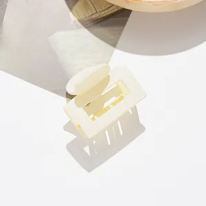 Détail d'une pince à cheveux mate carrée crème avec design creux et ressort en métal