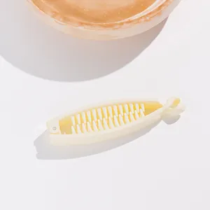 Détail d'une pince banane en résine blanc cassé avec double rangée de dents imbriquées