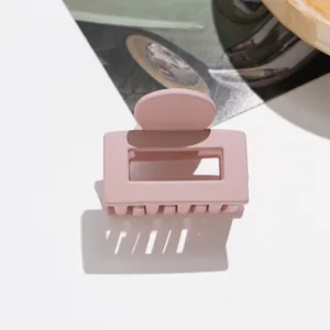 Détail d'une pince à cheveux carrée mate rose poudré avec design ajouré sur fond blanc