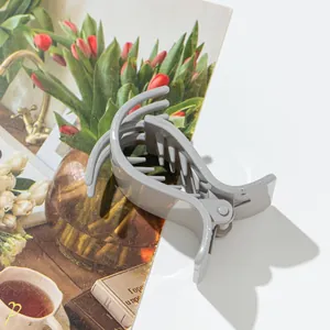 Gros plan d'une pince à cheveux en résine gris mat avec design à dents sur fond floral