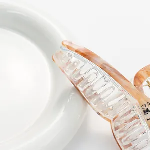 Elegante pinza per capelli in resina ambra marmorizzata con design multi-dente su piatto