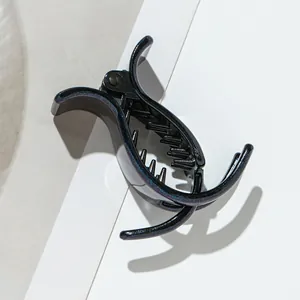 Close-up of a small black shark clip with blue and purple glitter for high ponytail hair
