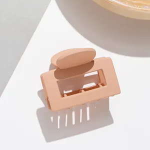 Détail d'une pince à cheveux rectangulaire rose mat avec design évidé et mécanisme à ressort