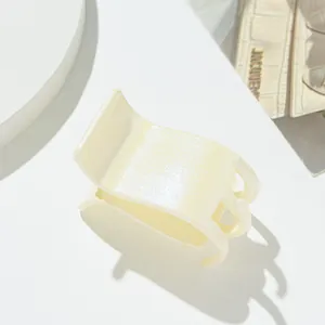 Gros plan sur la pince à cheveux crème pailletée avec finition nacrée et texture résine