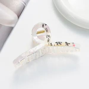 Dettaglio della molletta per capelli bianco perla con calligrafia e molla in oro