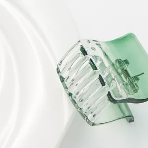 Transparent dark green shark hair claw clip made of resin with metal spring on white plate